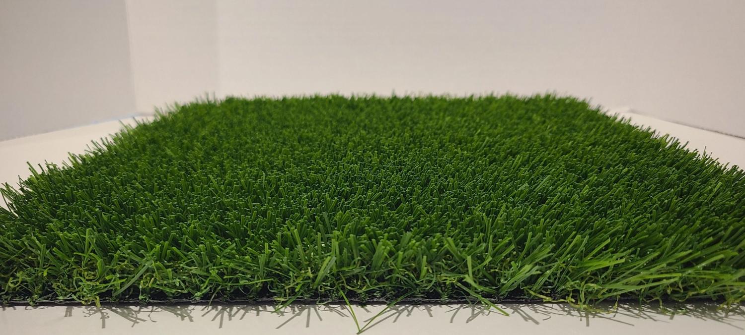 Close-up view of artificial grass showing dense green fibers, realistic texture, and layered blades designed for landscaping or sports surfaces.
