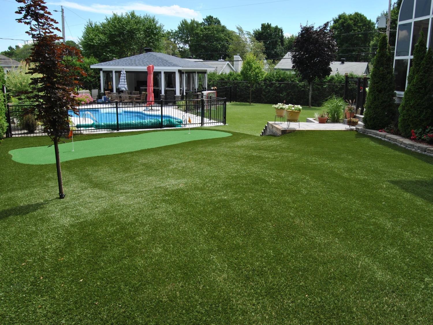 Spacious backyard with artificial grass lawn, custom putting green, swimming pool, and landscaped outdoor entertainment area.
