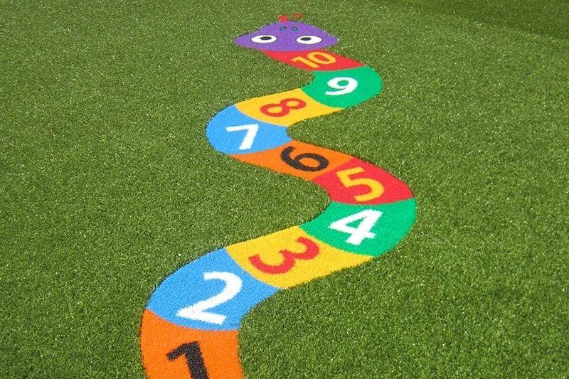 Colorful numbered snake design on artificial turf, featuring bright segments labeled from 1 to 10, commonly used for children's playground or learning activities.