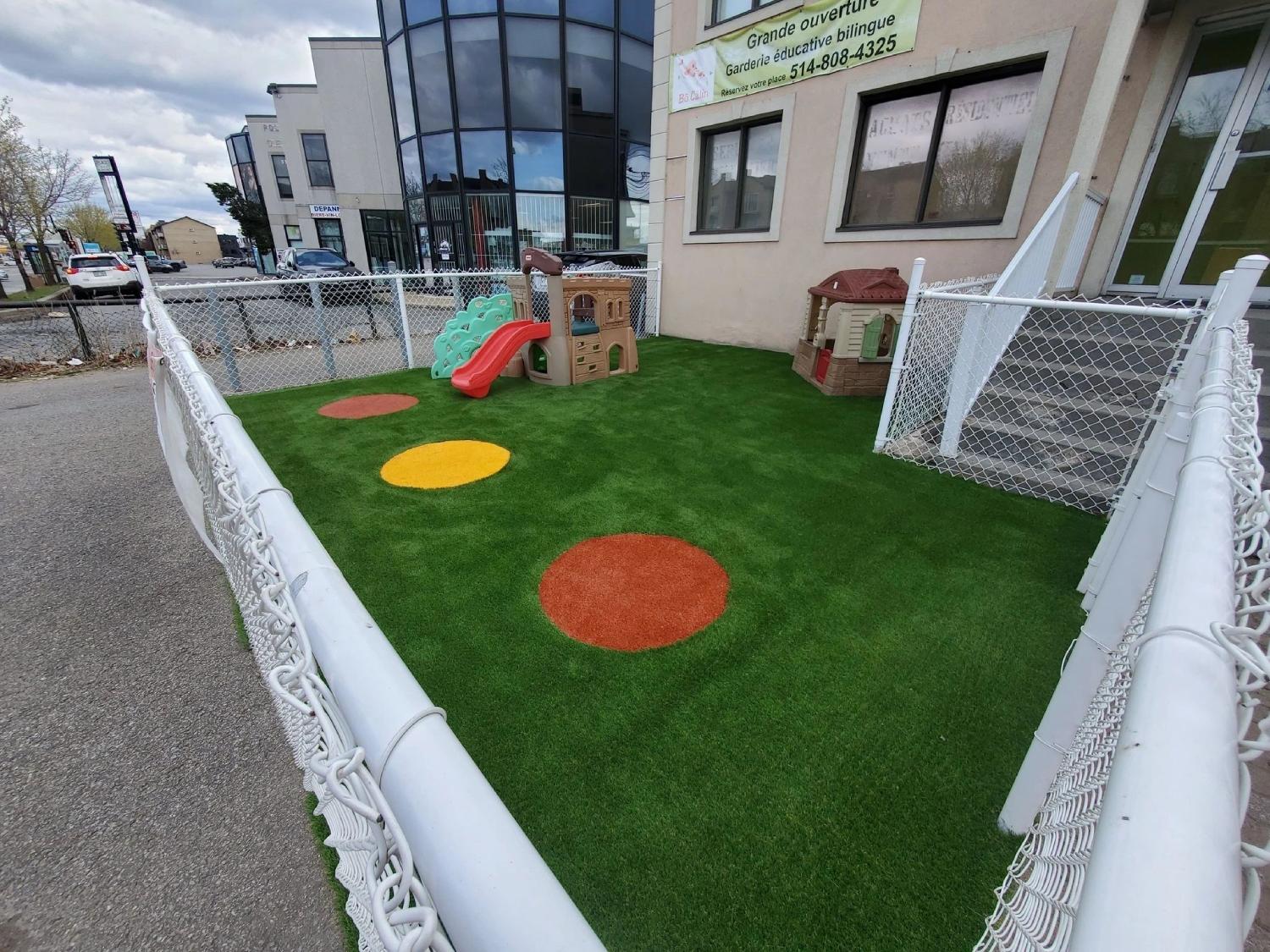 Safe daycare playground with artificial grass surface, colorful play zones, children’s equipment, and secure fenced outdoor play area.