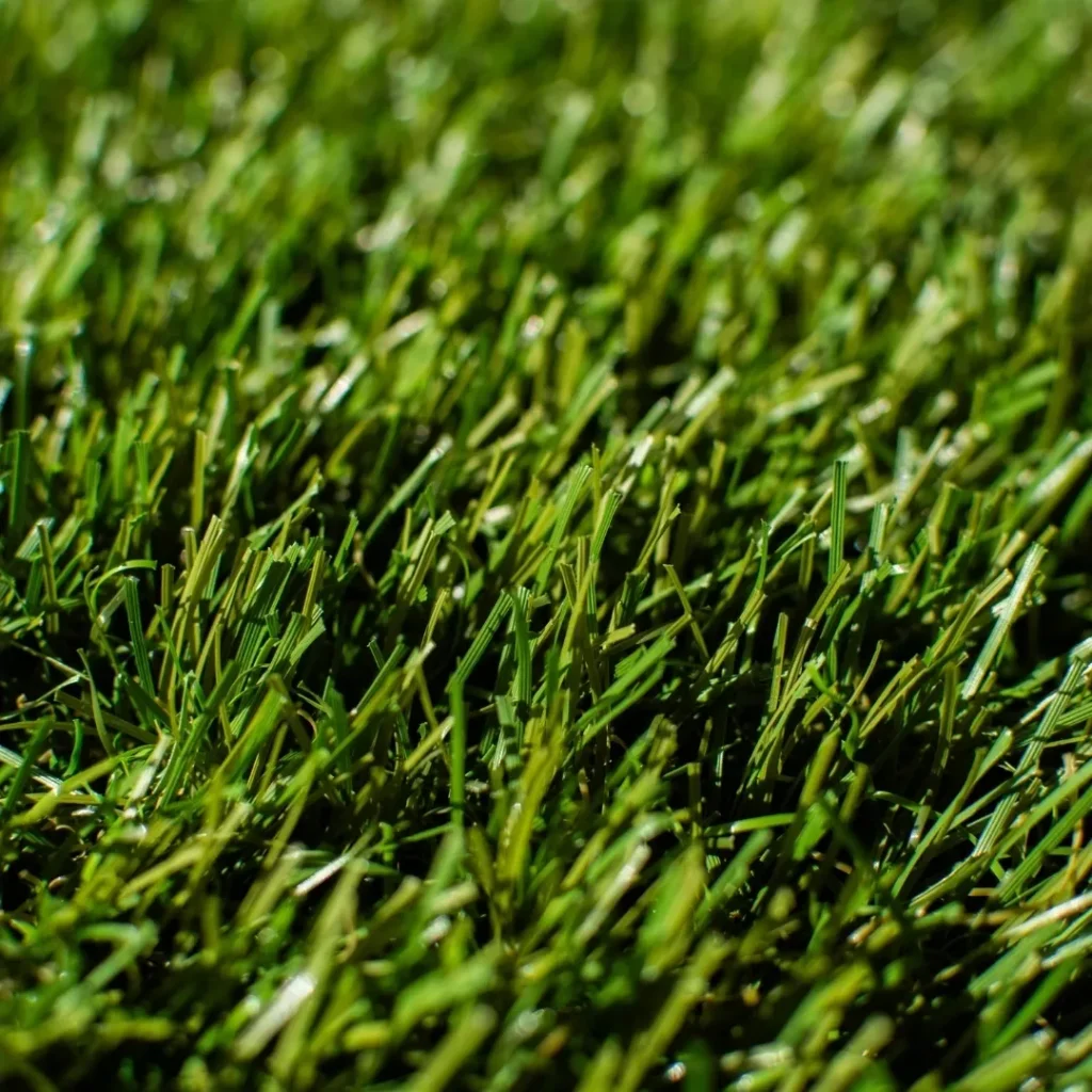 Close-up of premium artificial grass with varied green tones and realistic blades, designed to mimic natural lawn texture.