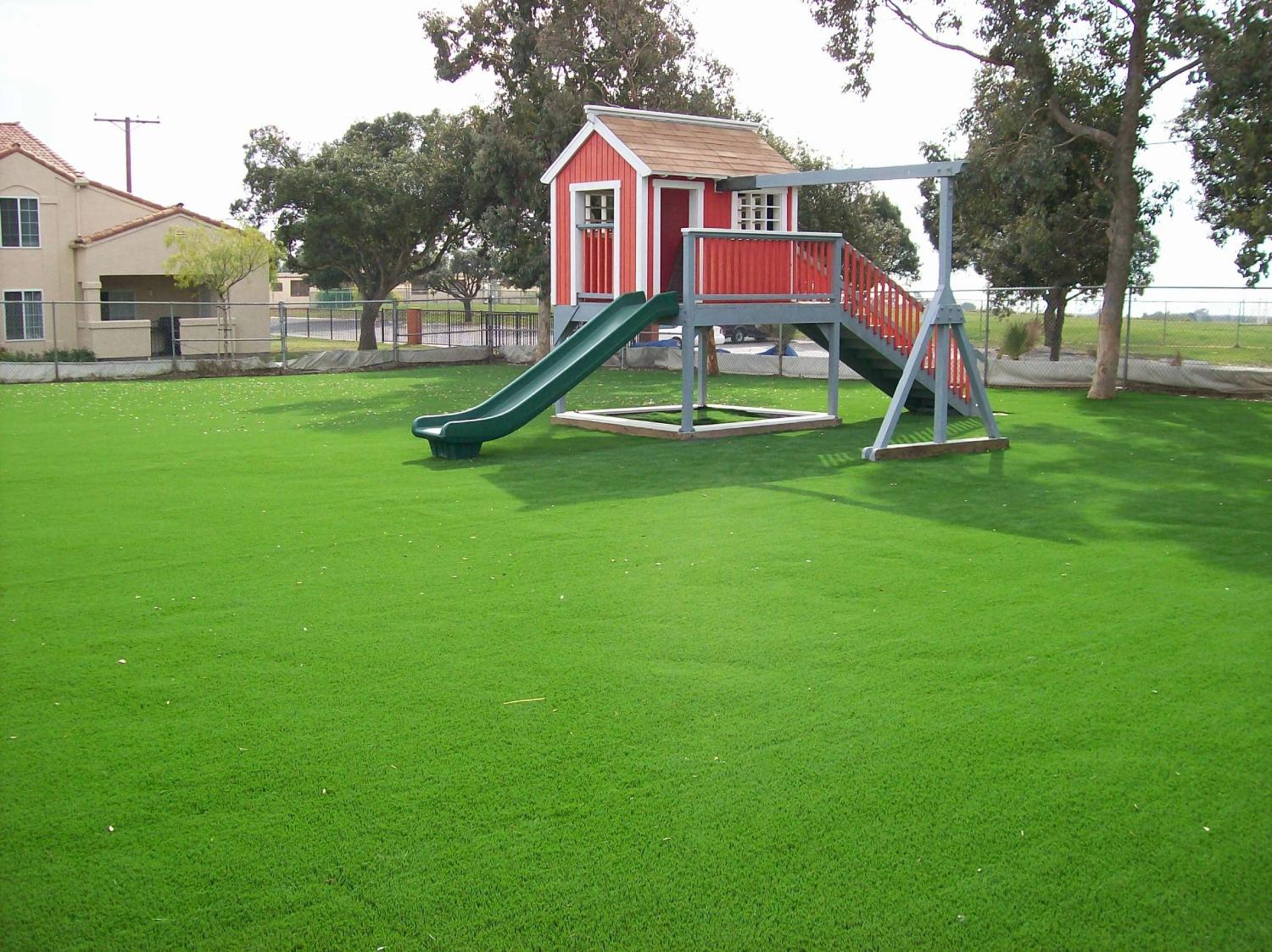 Spacious playground with artificial grass lawn, children’s playhouse, slide, and safe outdoor recreational area for families and schools.