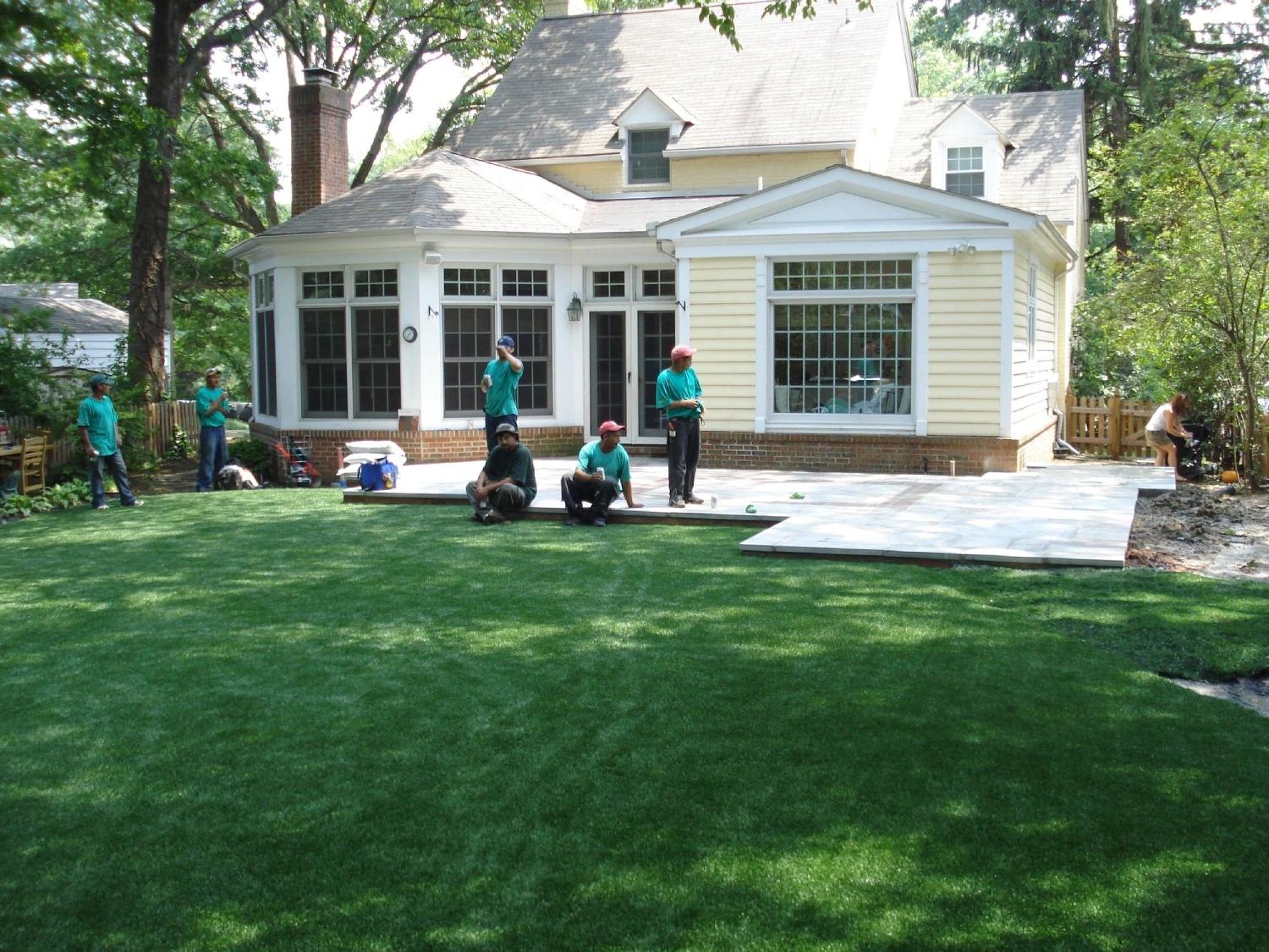 Residential backyard with newly installed artificial turf lawn, patio area, and landscaping project at a suburban home.