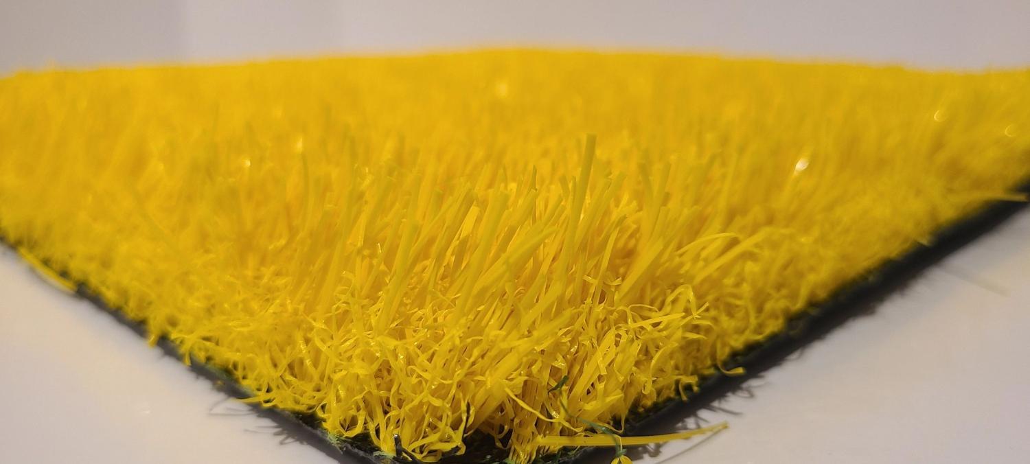 Close-up view of yellow artificial grass with dense synthetic fibers and vibrant color, used for decorative surfaces and sports applications.